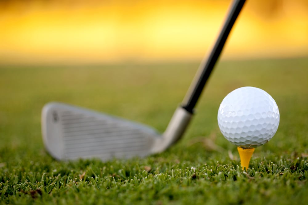 club and white golf ball over grass outdoors